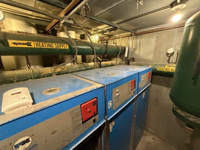 Commercial boiler units and heating infrastructure in a Chicago high-rise mechanical room before upgrades.
