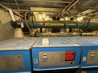Mechanical Penthouse Heating System - Before Photo Old commercial heating boilers and supply pipes in the Lake Point Tower mechanical penthouse before an HVAC system replacement.