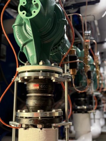 A detailed close-up of heavy-duty rubber expansion joints and vibration isolators installed on the hydronic piping for the new commercial boiler pumps at Lake Point Tower.