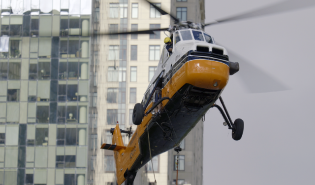 Following a successful rooftop delivery, a heavy-duty helicopter makes its descent along the glass exterior of Lake Point Tower to retrieve the next commercial boiler for the massive Chicago HVAC upgrade.