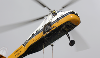 Chicago Commercial HVAC - Close-Up Rooftop Boiler Delivery A striking close-up view of a heavy-duty helicopter precisely delivering a high-efficiency commercial boiler to the rooftop of Lake Point Tower during a massive Chicago HVAC upgrade.