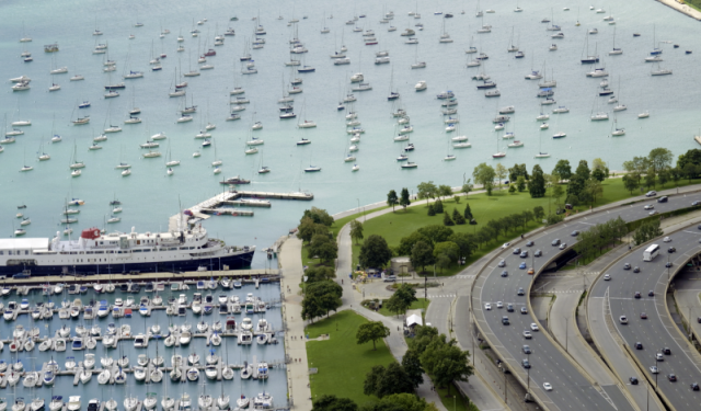 Aerial view of Chicago's marine and transportation infrastructure, featuring docked vessels at Monroe Harbor and commercial traffic along Lake Shore Drive.