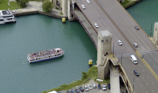 Chicago River Transit Infrastructure - Lake Shore Drive Bridge Aerial view of the Lake Shore Drive bridge over the Chicago River, highlighting the city's structural transportation infrastructure and a commercial passenger boat navigating the waterway.
