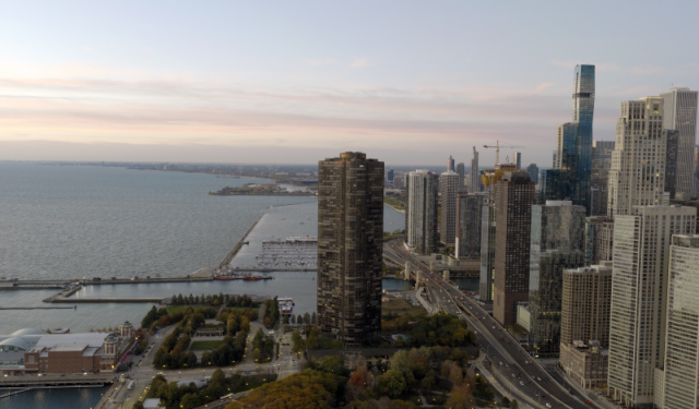 Wide aerial view of the Chicago skyline and Lake Shore Drive at sunrise, showcasing the city's extensive commercial and residential high-rise infrastructure along Lake Michigan.