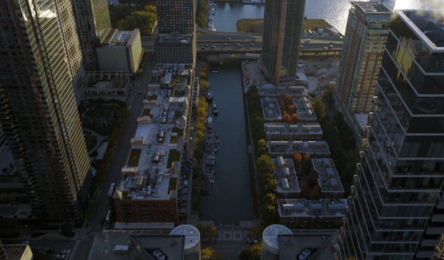 High-angle aerial view of the Chicago River cutting through dense downtown commercial real estate and high-rise infrastructure.