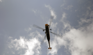 Chicago Commercial HVAC - Helicopter Rigging Descent A heavy-duty helicopter descends back toward a secured downtown staging area to rig the next high-efficiency commercial boiler for the massive rooftop HVAC upgrade at Lake Point Tower.