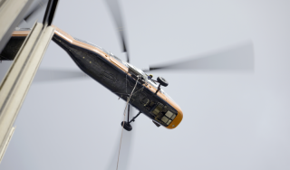 Chicago Commercial HVAC - Helicopter Descent for Rigging Following a successful rooftop delivery, a heavy-duty helicopter makes its descent along the glass exterior of Lake Point Tower to retrieve the next commercial boiler for the massive Chicago HVAC upgrade.