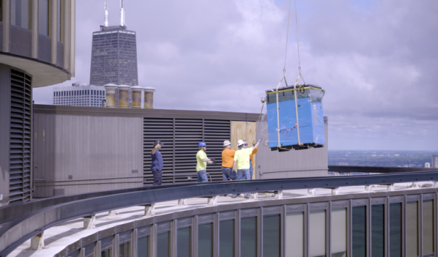 A heavy-duty helicopter successfully delivers the first high-efficiency commercial boiler to the rooftop of Lake Point Tower, marking a major milestone in a massive Chicago HVAC upgrade.