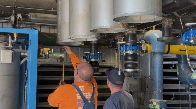 Commercial HVAC technicians measuring custom piping connections for a new P-K boiler installation at Lake Point Tower.