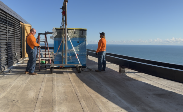 Commercial HVAC technicians using a gantry crane for a rooftop P-K boiler installation at Lake Point Tower in Chicago.